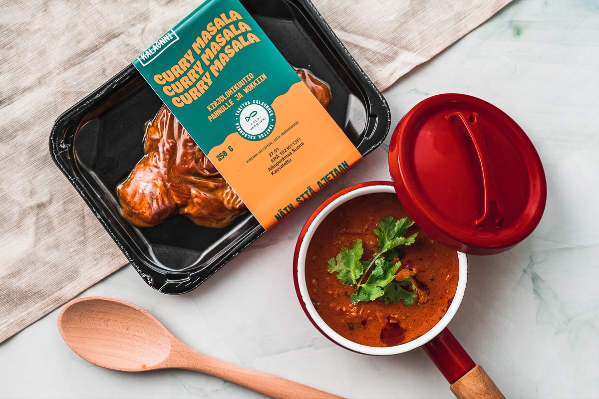 Kalaonnen Curry masala -kirjolohipalapakkaus ja siitä valmistettu keitto kattilassa.